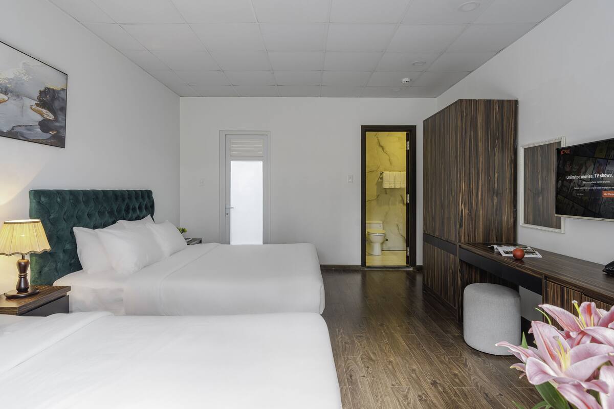 Habitación de hotel con una cama grande, un escritorio, un televisor y un baño visible a través de una puerta abierta.