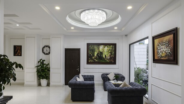 A modern living room with dark sofas, a chandelier, and artwork on the walls. - TTR Moonstone Apart Hotel (Xuan Huong - Da Lat)