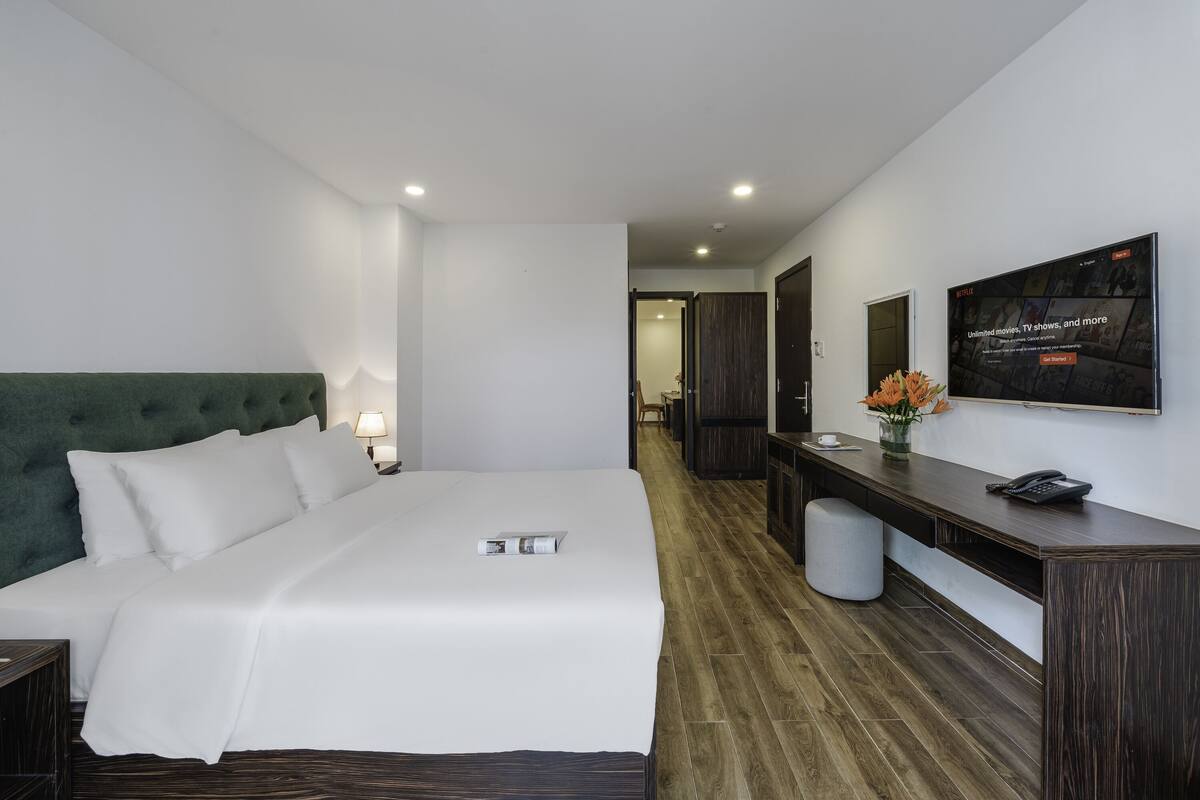 Una habitación de hotel moderna con una cama grande, un escritorio y una televisión en la pared.