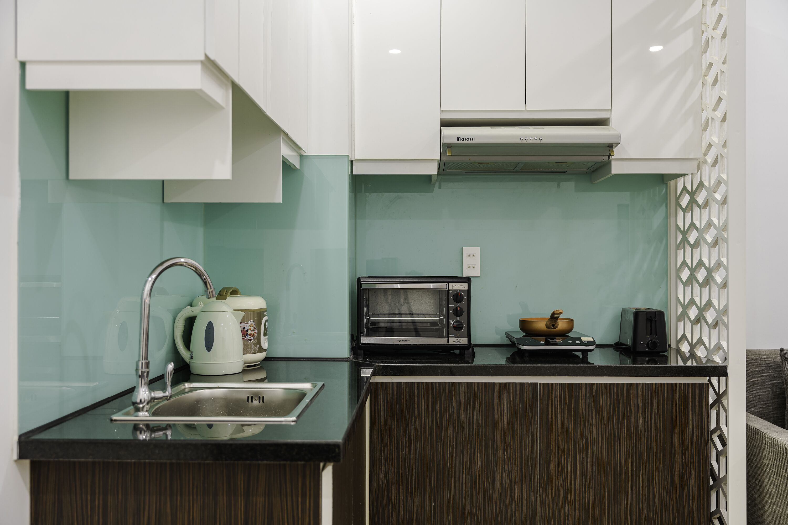 A kitchen with a sink, a kettle, a toaster, and a microwave.