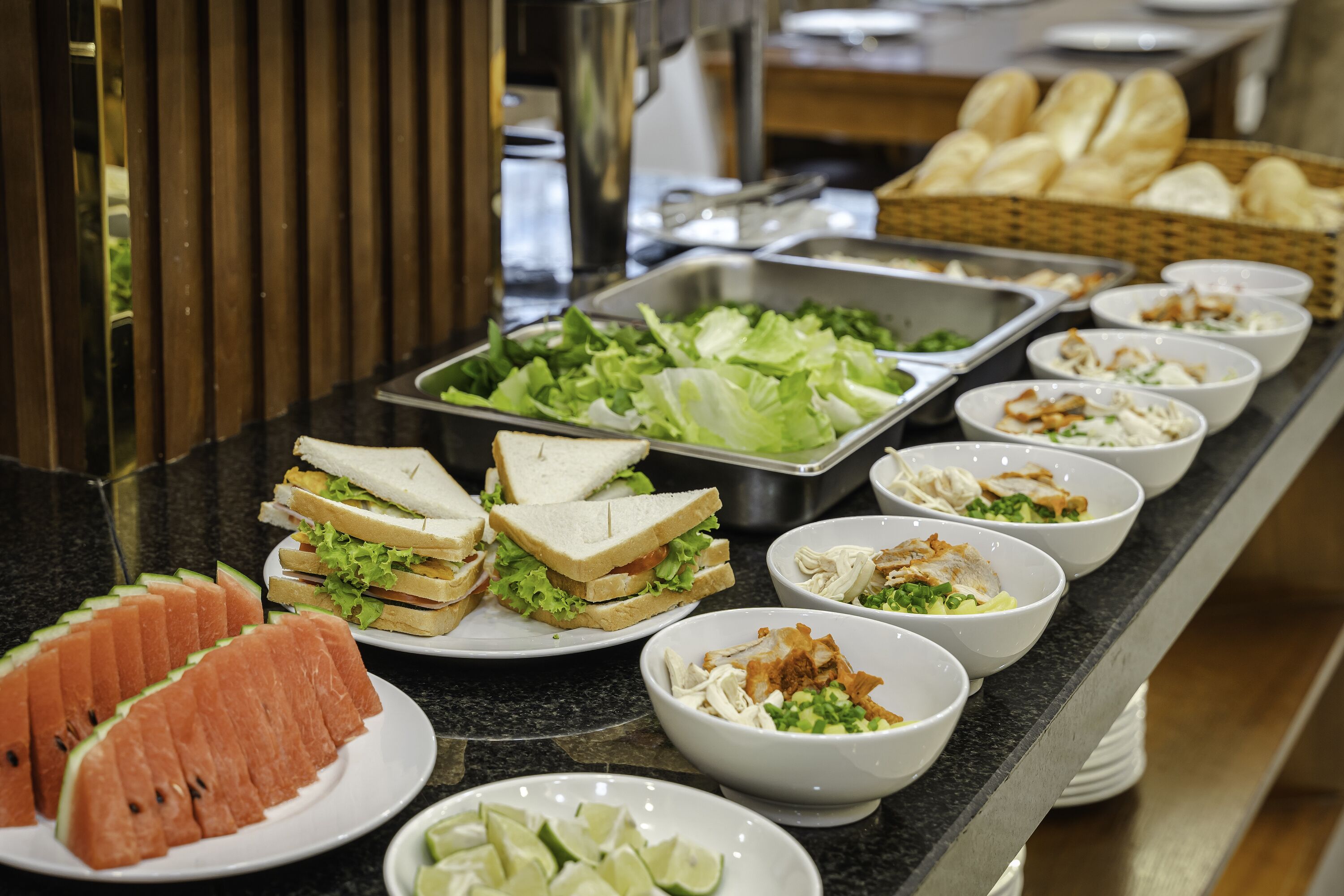 A buffet with various food items including sandwiches, salads, and bowls of food.