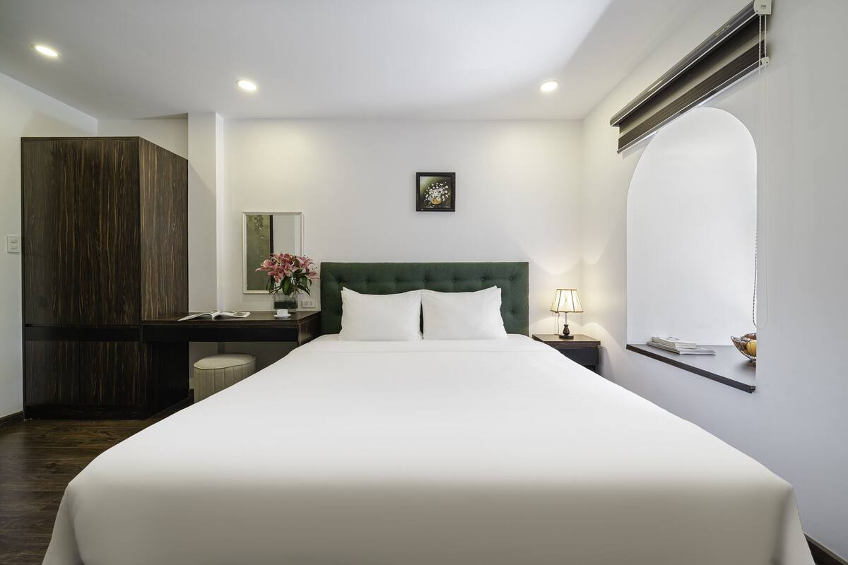 Habitación de hotel ordenada con una cama grande, un escritorio, un armario y una ventana con vistas.