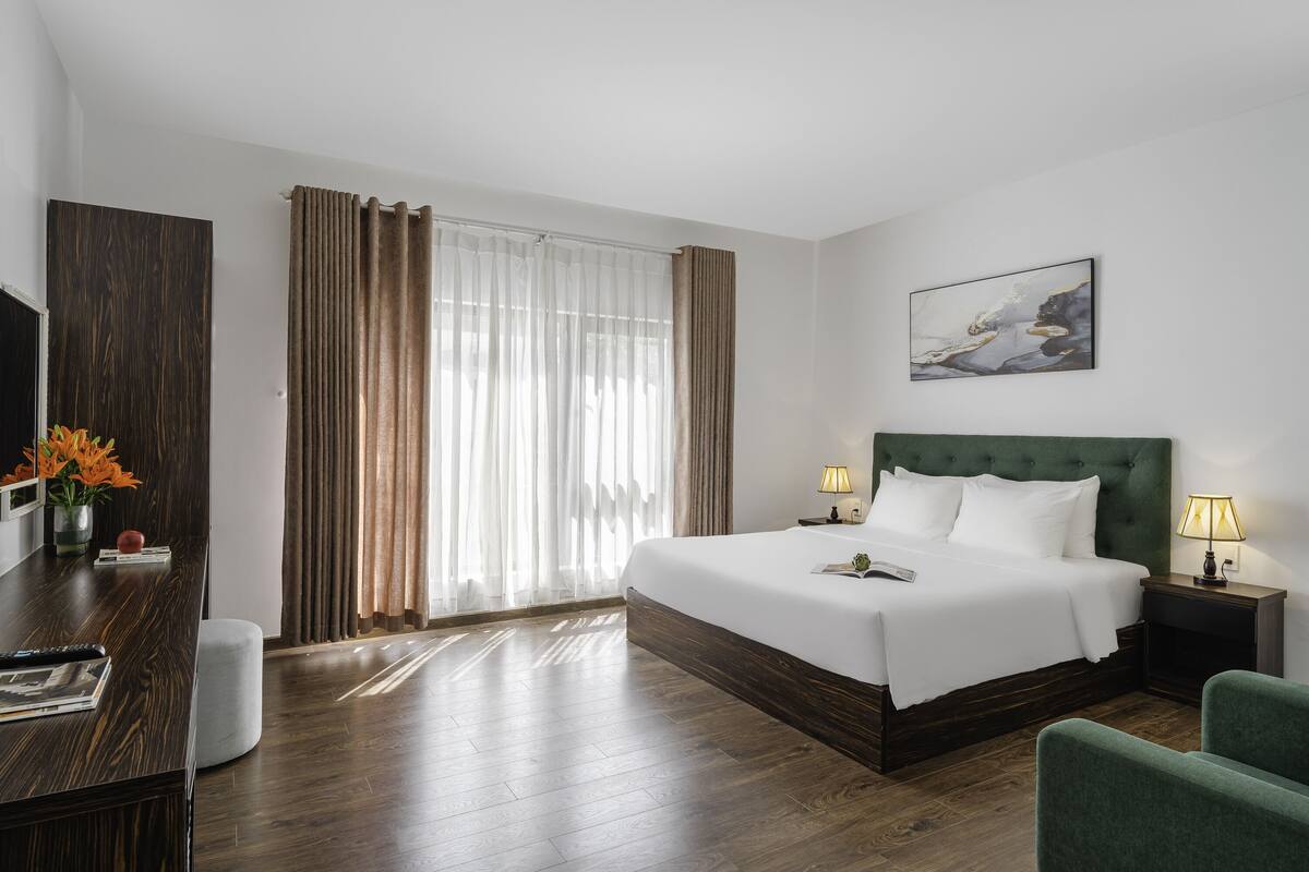 Habitación de hotel con una cama grande, un escritorio con silla, un televisor y un cuadro en la pared.