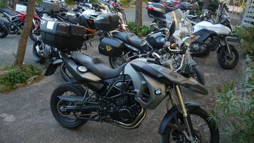 A parked BMW F800GS motorcycle with a luggage rack, in a parking lot with other motorcycles and cars.