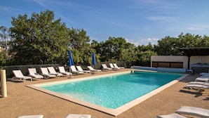 A rectangular swimming pool with clear blue water, surrounded by lounge chairs and umbrellas. - Hotel Les Persedes Sud Ardeche (Lavilledieu)