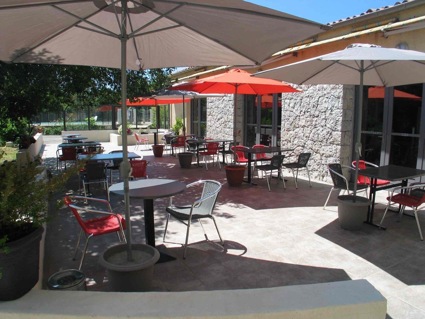 An outdoor patio area with tables and chairs, some with umbrellas.