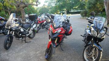 Una hilera de motocicletas estacionadas en un estacionamiento, con árboles al fondo.