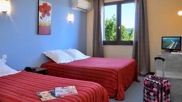 Habitación de hotel con dos camas, una ventana con cortinas, un televisor y una maleta.