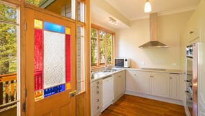 A kitchen with wooden cabinets, a microwave, and a stainless steel range hood. - Mataura Lodge | Your Private Rural  Retreat (Athol)