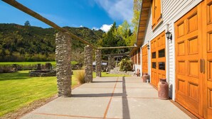 A building with a stone archway, a concrete pathway, and wooden garage doors. - Mataura Lodge | Your Private Rural  Retreat (Athol)