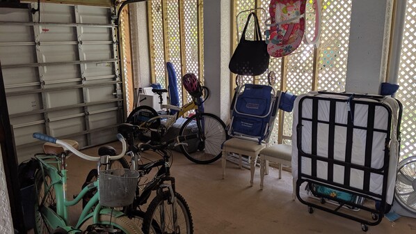 A storage area with bicycles, a stroller, and a cart. - Keys stilt house top floor unit (Naples)