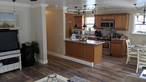 A modern kitchen with wooden cabinets, a stainless steel microwave, and a built-in oven. - Keys stilt house top floor unit (Naples)
