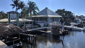 A waterfront restaurant with outdoor seating, a dock, and boats. - Keys stilt house top floor unit (Naples)