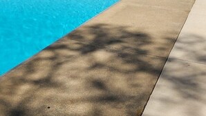 A rectangular swimming pool with clear blue water, surrounded by a white fence, and a gazebo with a beige umbrella in the background. - Paradise Lake Michigan Beach home with inground pool,  hot tub, sleeps 20 (Norton Shores)