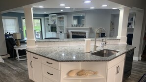 A modern kitchen with a granite countertop, white cabinetry, and a built-in sink. - Paradise Lake Michigan Beach home with inground pool,  hot tub, sleeps 20 (Norton Shores)