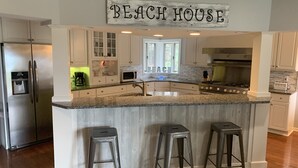 A kitchen with a granite countertop, stainless steel appliances, and a 'Beach House' sign. - Paradise Lake Michigan Beach home with inground pool,  hot tub, sleeps 20 (Norton Shores)