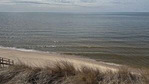 A beach with a wooden walkway leading to the water, surrounded by dry grass. - Paradise Lake Michigan Beach home with inground pool,  hot tub, sleeps 20 (Norton Shores)