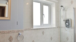 A bathroom with a glass-enclosed shower, a sink with a soap dispenser, and a window above the bathtub. - 1 bedroom accommodation in Bowness-on-Windermere (Bowness-on-Windermere)