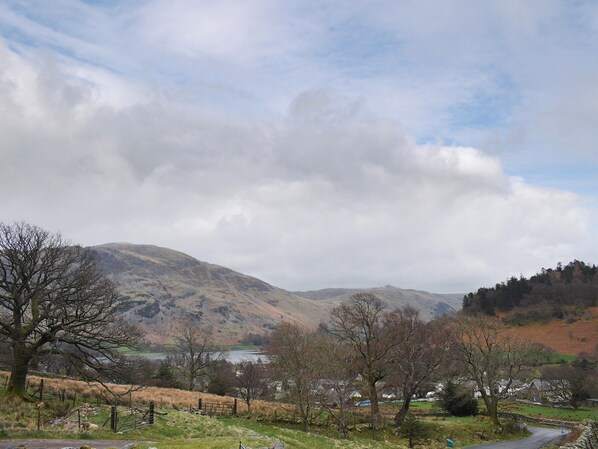 A rural landscape with a lake, mountains, and a small village.