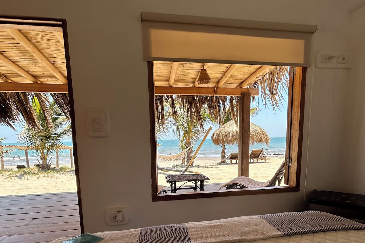 Ein Zimmer mit einem Bett, einem Fenster mit Meerblick und einem Deckenventilator.