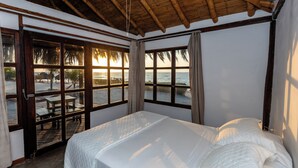 Une chambre avec un grand lit, une vue sur la plage et un plafond en bois.