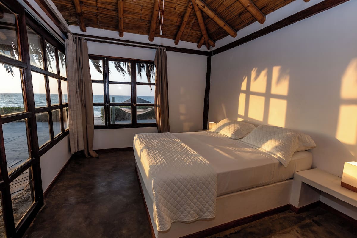 Ein Schlafzimmer mit großem Fenster, einem Bett und einem Nachttisch.
