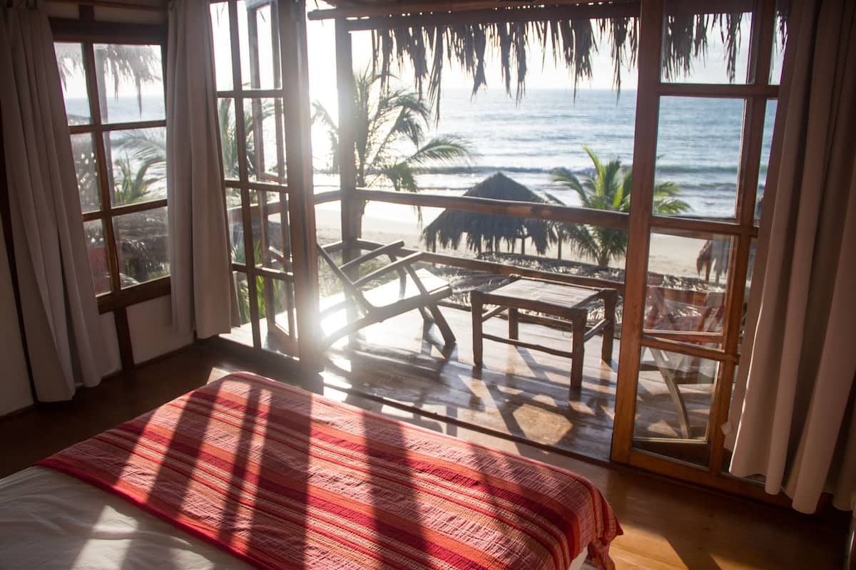 Ein Zimmer mit Bett, Meerblick und einem Tisch mit Stühlen.