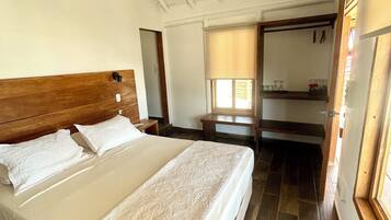 Ein Schlafzimmer mit einem Holzkopfteil, einem großen Bett mit weißer Bettwäsche, einem Deckenventilator und einem Fenster mit Jalousien.