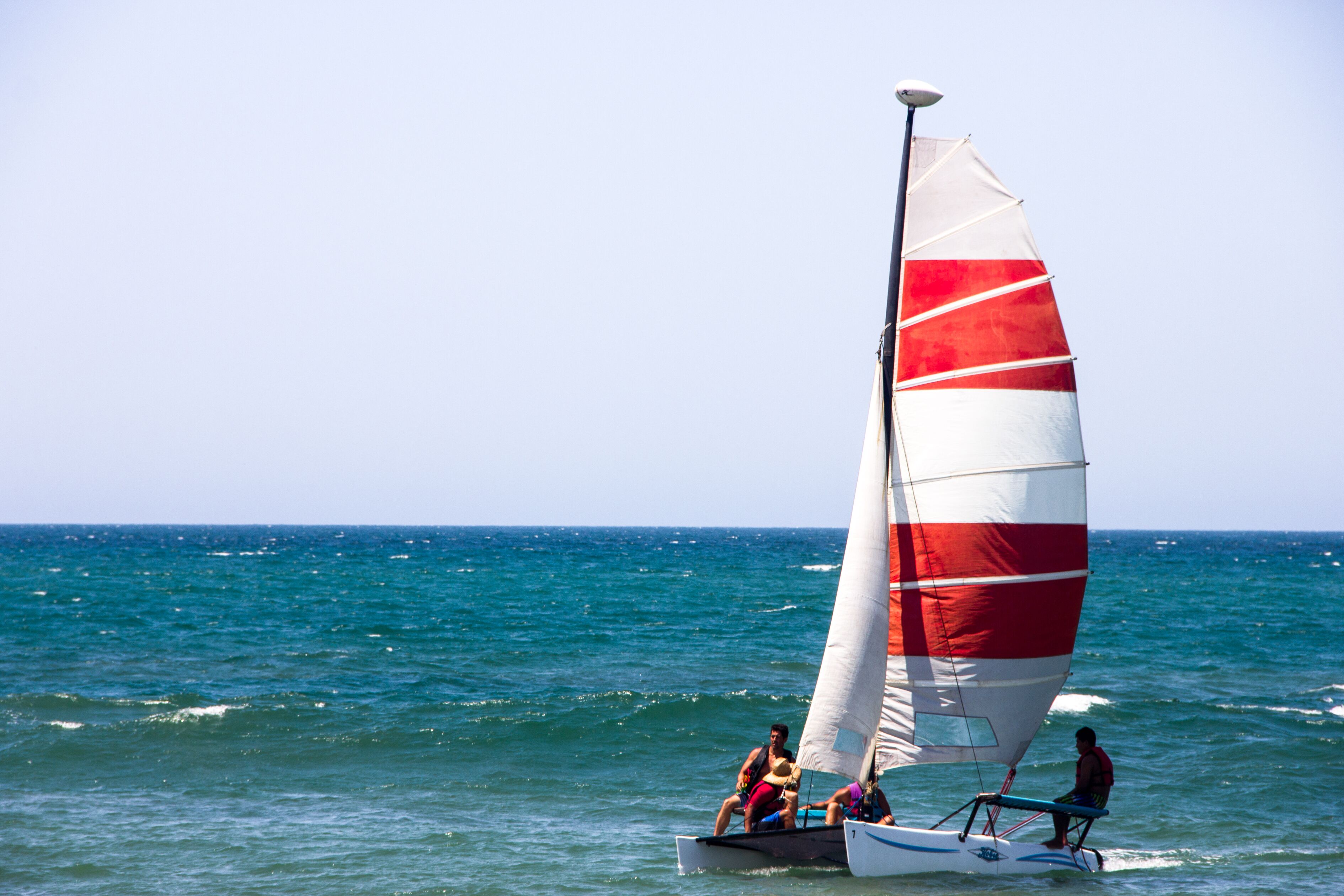 Un velero con vela roja y blanca sobre el agua.