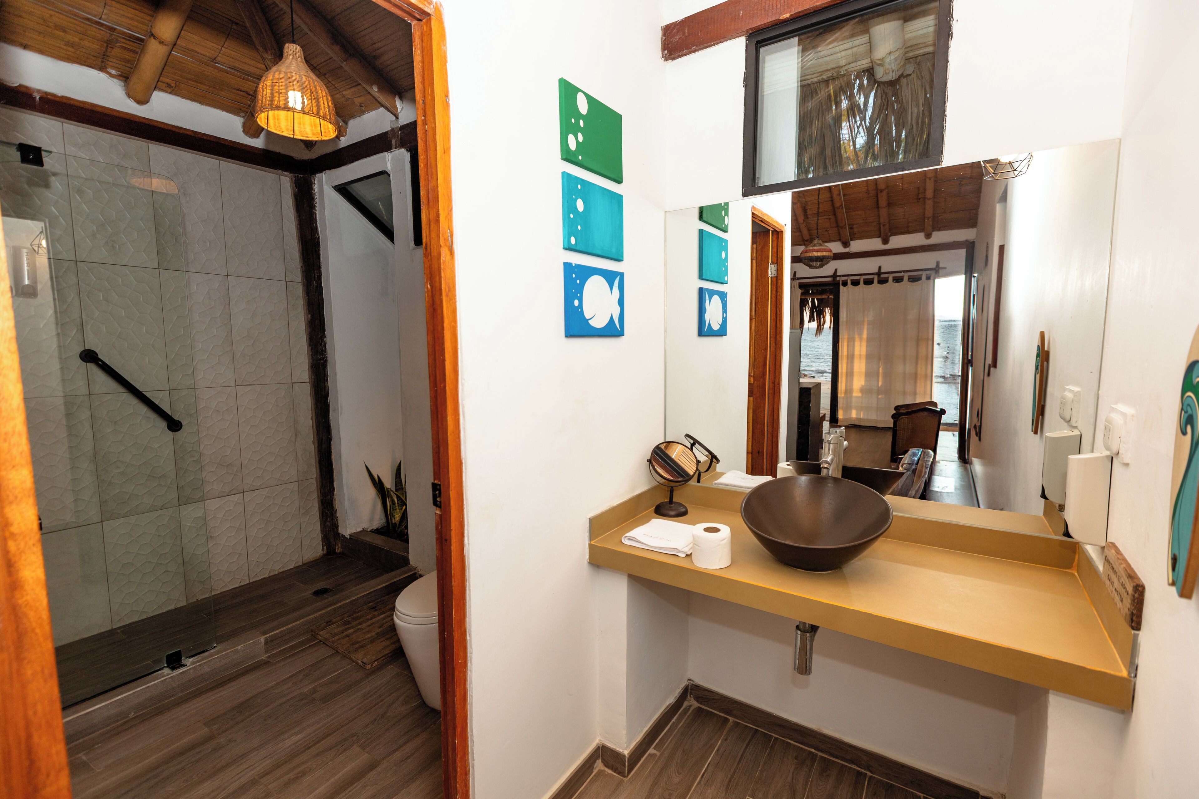 Bany amb dutxa, un lavabo amb un mirall gran i un penjador de tovalloles.