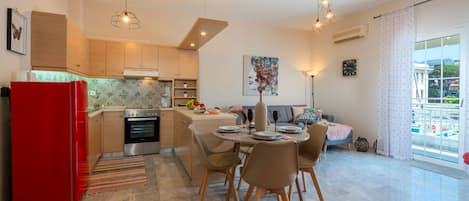 Enjoy a compact yet functional space with a kitchen, dining area, and living space, featuring a sofa, coffee table, and round dining table with four chairs.