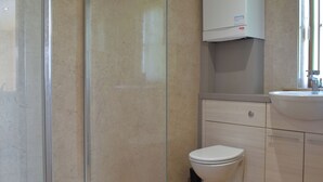 A bathroom with a glass shower enclosure, a toilet, a sink, and a cabinet. - 2 bedroom accommodation in Chard (Chard)