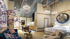 Ein geräumiges Hotelzimmer mit einem großen Bett, zwei Sofas, einer Essecke und einem Chandelier.