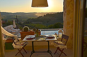 Enjoy a romantic outdoor dining experience with a table set for two on this serene terrace overlooking the rolling hills.