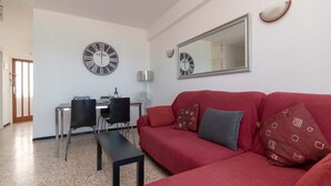 Ein Wohnzimmer mit einem roten Sofa, zwei schwarzen Sesseln, einem kleinen Tisch und zwei Wanduhren.