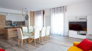 A modern living space with a dining area, kitchen, and entertainment unit.