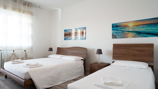 Two single beds with white linens, wooden headboards, and bedside tables with lamps.