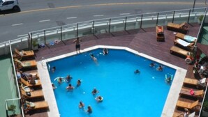 A rooftop swimming pool with wooden loungers and a view of the street. - Radar Cabo Corrientes (Mar del Plata)