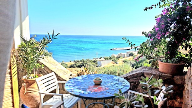 Un patio con una mesa redonda y sillas, con vista al mar.