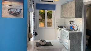 Una cocina moderna con una mesa blanca, una lámpara colgante y vistas al exterior a través de una ventana.