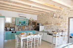 A kitchen with teal cabinets, a stone wall, and a wooden ceiling.