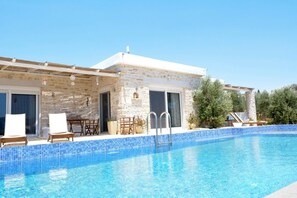 A stone building with a swimming pool, outdoor seating, and a pergola.