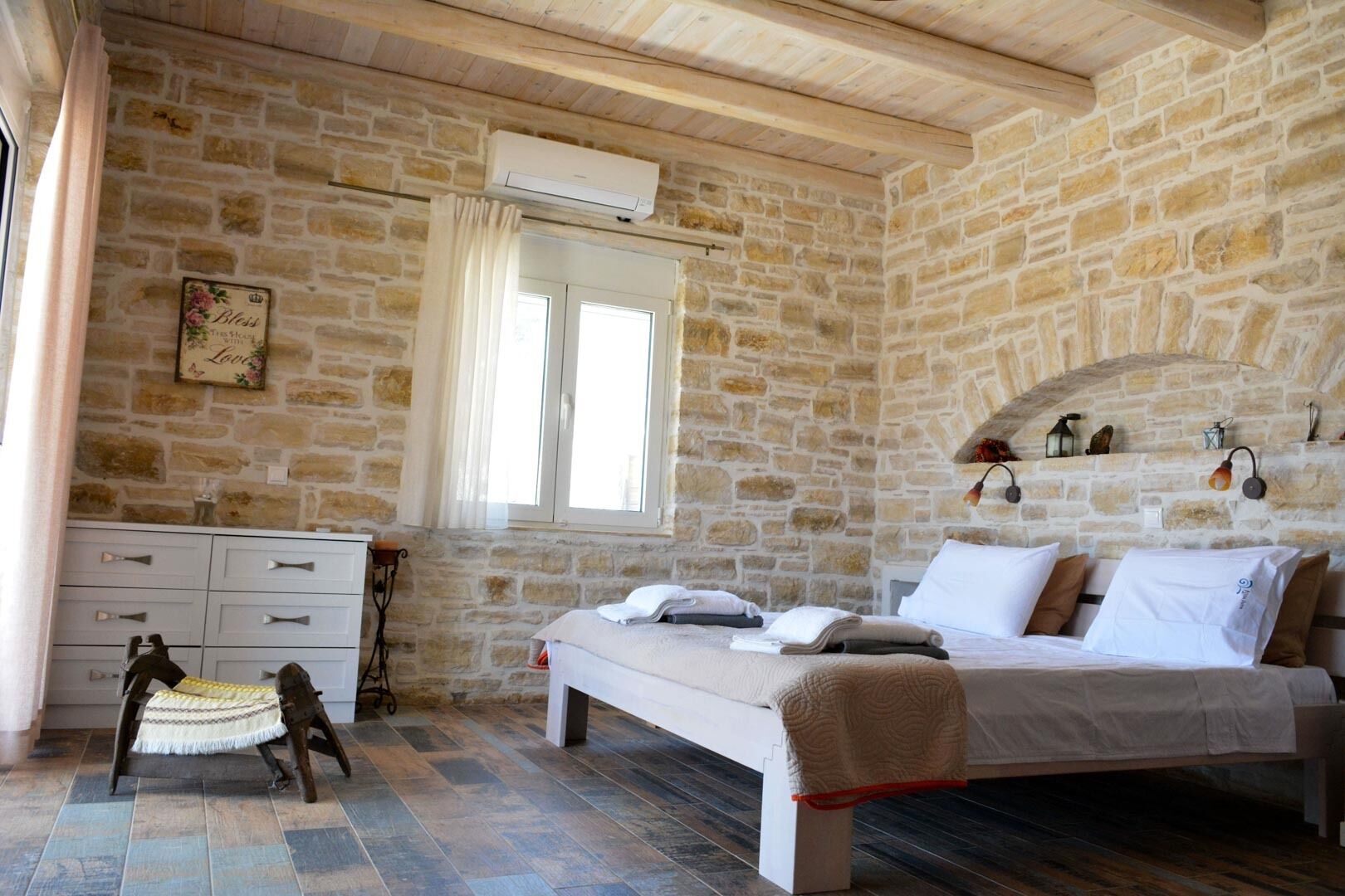 A stone-walled bedroom with a bed, a dresser, and a window.