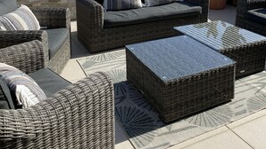 Une terrasse sur le toit, aménagée avec des meubles en osier, un cactus et offrant une vue sur une ville côtière et un château.