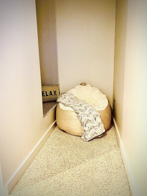 A small, narrow room with a single bean bag chair and a sign on the wall that reads "ELAX".
