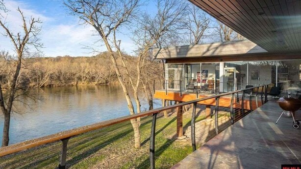 Una casa moderna amb hivernacle de vidre que fa vedar a un riu.