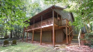 Une cabane en bois dotée d’un balcon, entourée d’arbres.