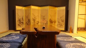Perinteinen japanilainen huone, jossa on tatamimatot, matala puupöytä ja shoji-seinä, jossa on kuvia vuorista.
