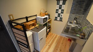 Pieni, käytännöllinen keittiö, jossa on mikroaaltouuni, vedenkeitin ja pesuallas.