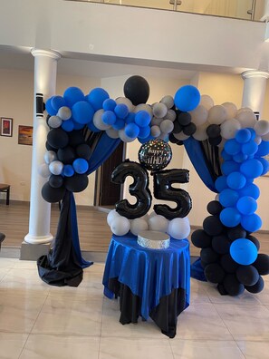 A decorated archway with balloons and a table with a blue tablecloth.